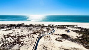 A coastal landscape with a sandy beach and a wooden boardwalk leading to a pier. - Beach Club Corner Unit! Direct Gulf View - Pools - Beach - Grill -Upgraded Cable (Gulf Shores)