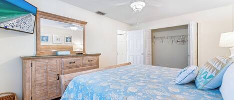 A bedroom with a bed, dresser, and a ceiling fan.