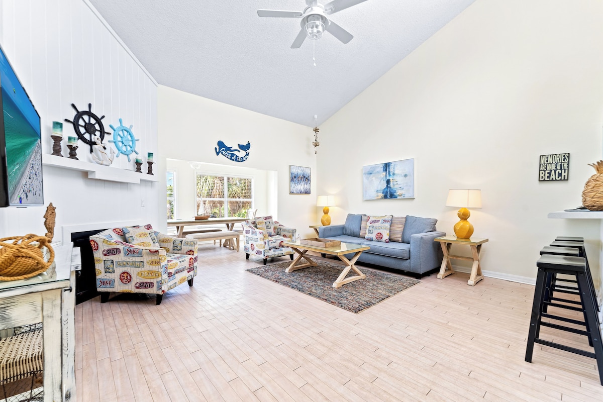 A spacious living room with a wooden floor, a blue sofa, a coffee table, and decorative wall art.