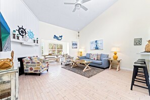 A living room with a blue sofa, a patterned armchair, a coffee table, and a ceiling fan.