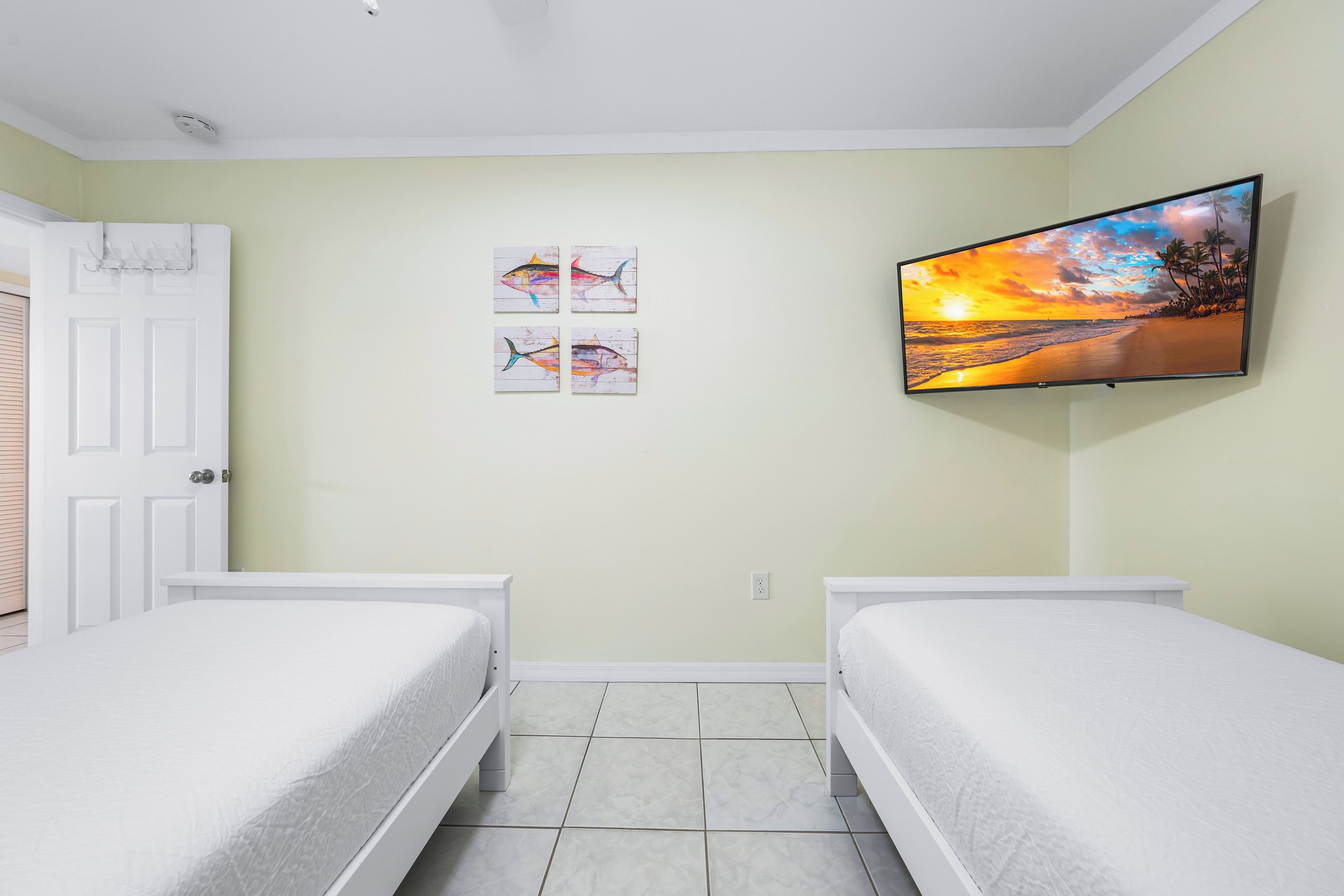 Una camera da letto con due letti, una TV montata a parete e opere d'arte sopra i letti.