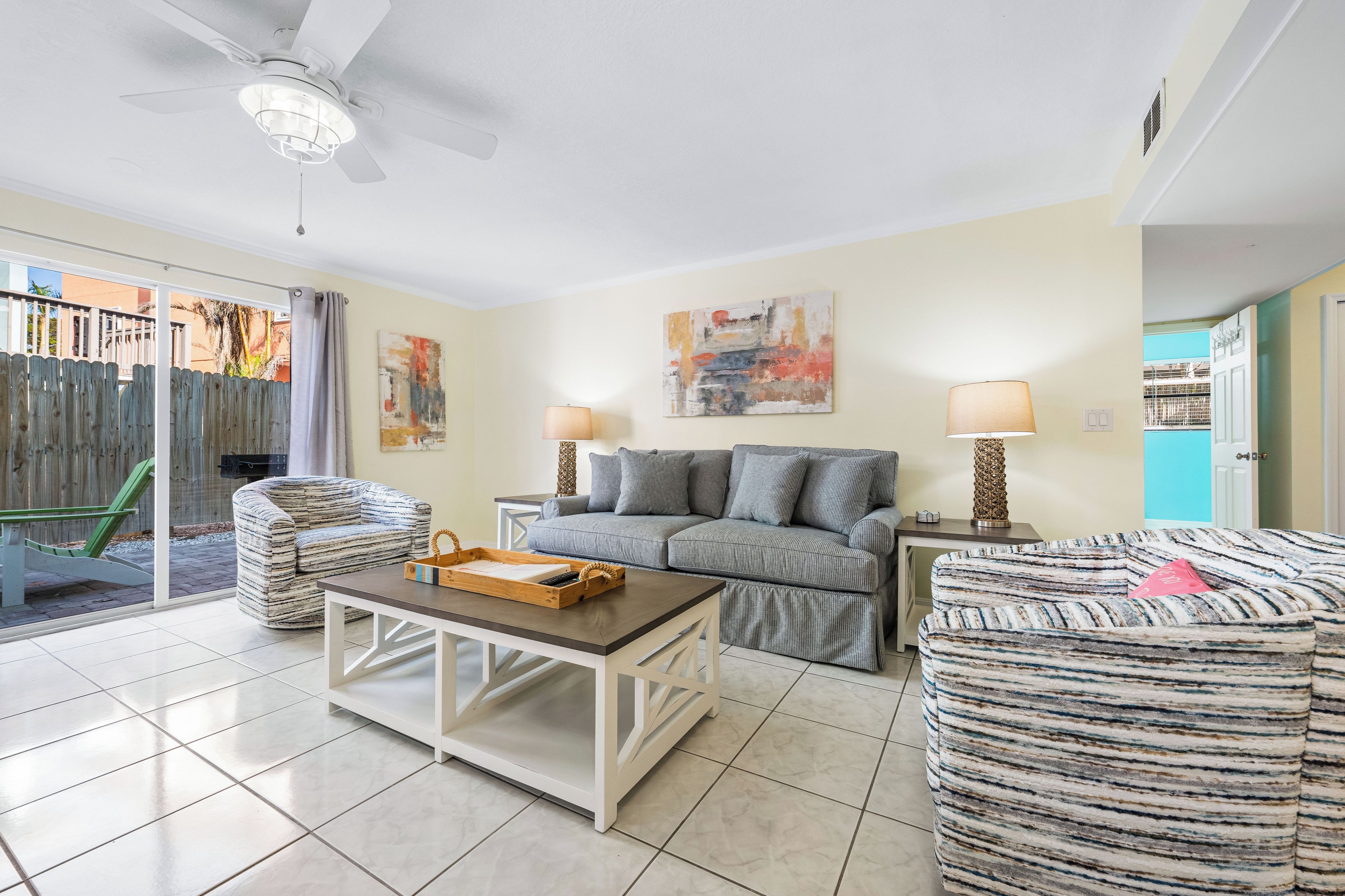 A living room with a sofa, a coffee table, and a chair. There is a sliding glass door leading to a patio area.