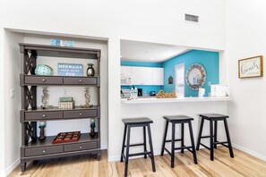 A modern kitchen with white cabinets, a blue accent wall, and a bar area with stools.