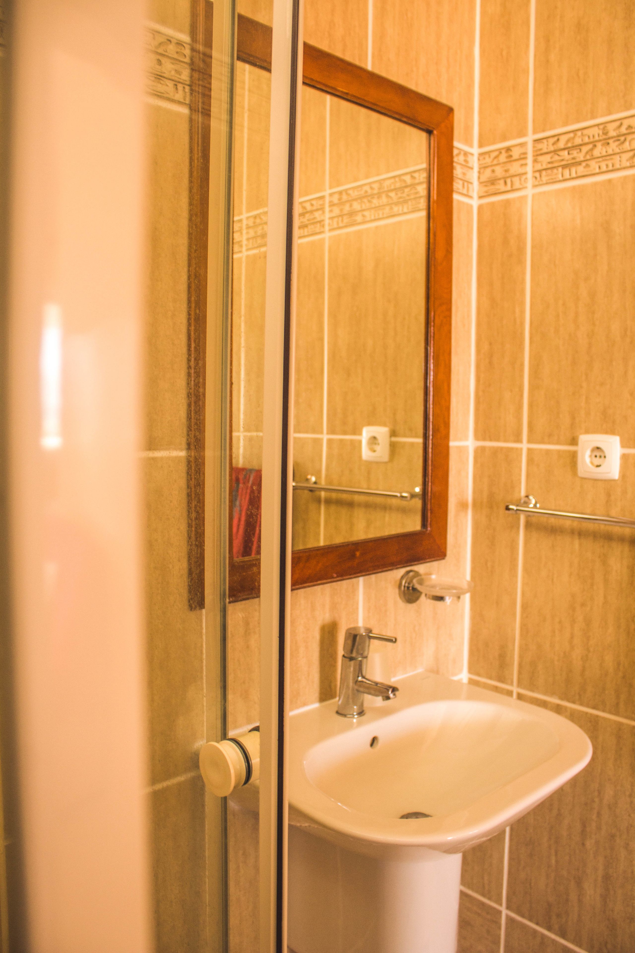 A bathroom with a white sink, a mirror with a wooden frame, and a towel rack.
