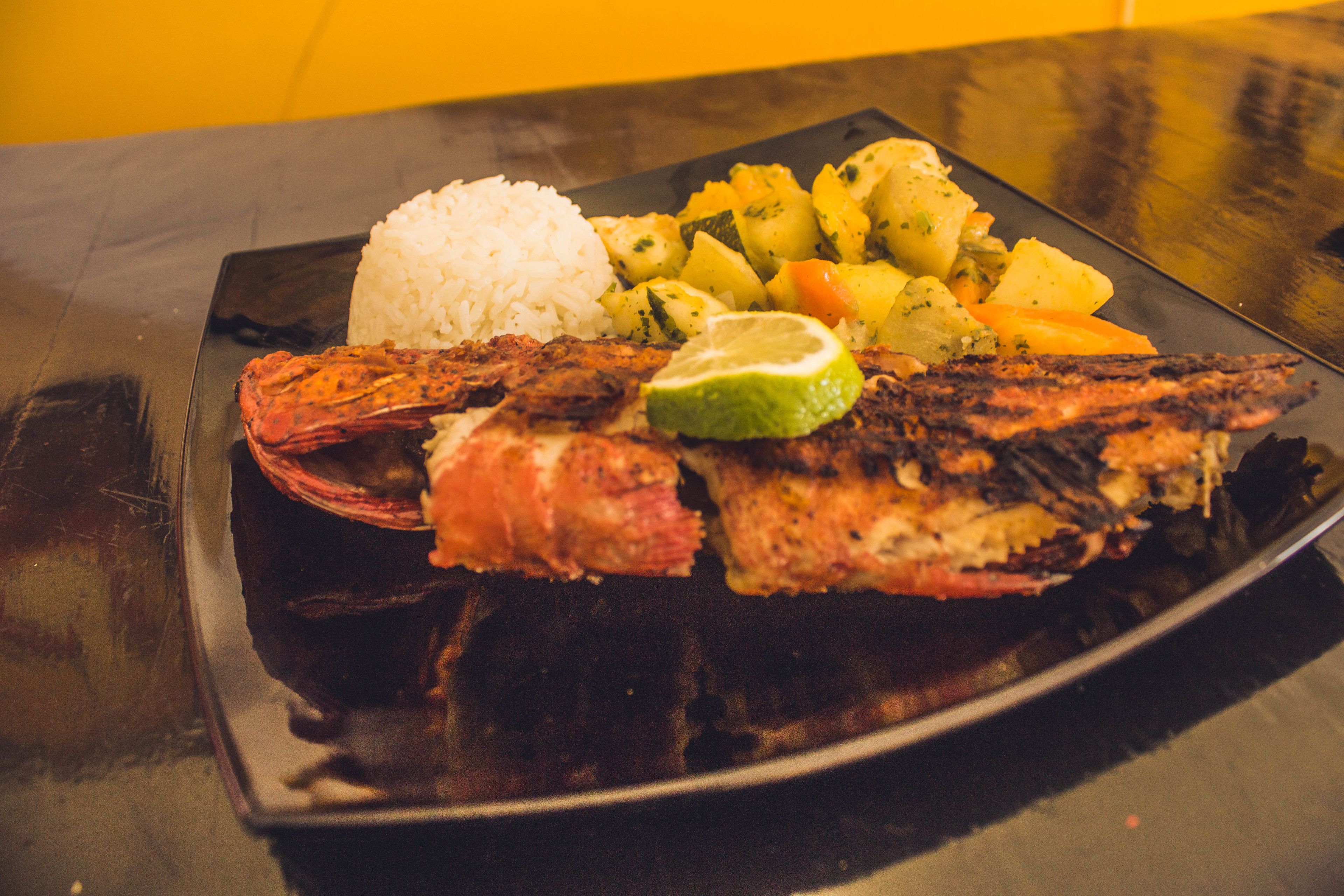 A plate with grilled fish, rice, and a side of vegetables.
