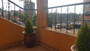 Ein Balkon mit Blick auf eine belebte Straße, einem Blumentopf und einem Metallgeländer.