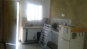 Eine kleine Küche mit Spüle, Fenster, Kühlschrank und einem Wäscheständer.