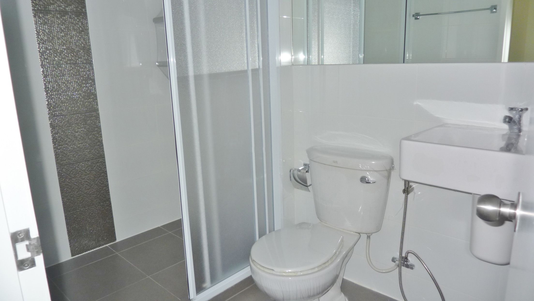 A bathroom with a toilet, a shower enclosure, and a sink.