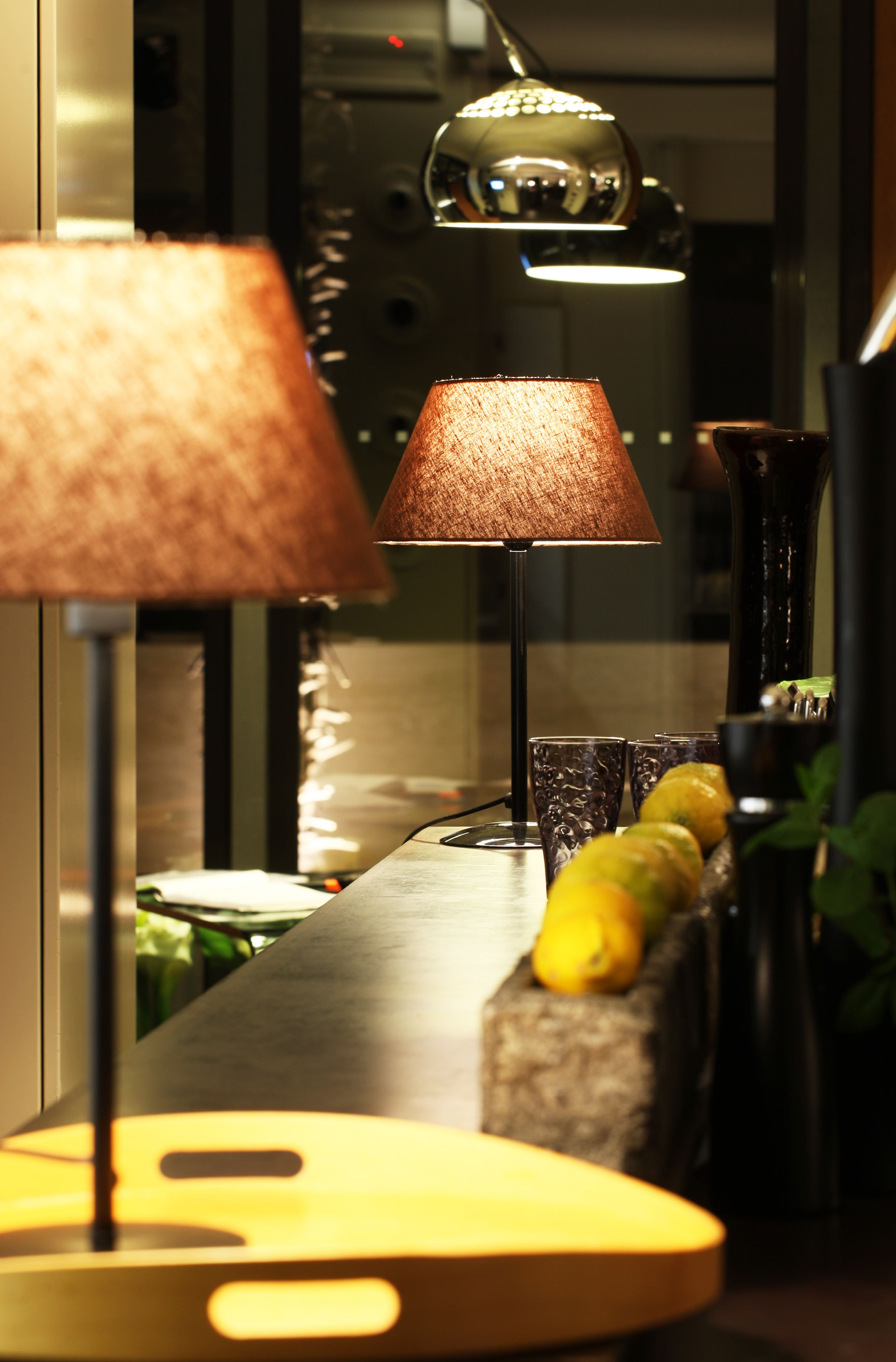 A bar area with two lamps, a fruit display, and a modern bar counter.