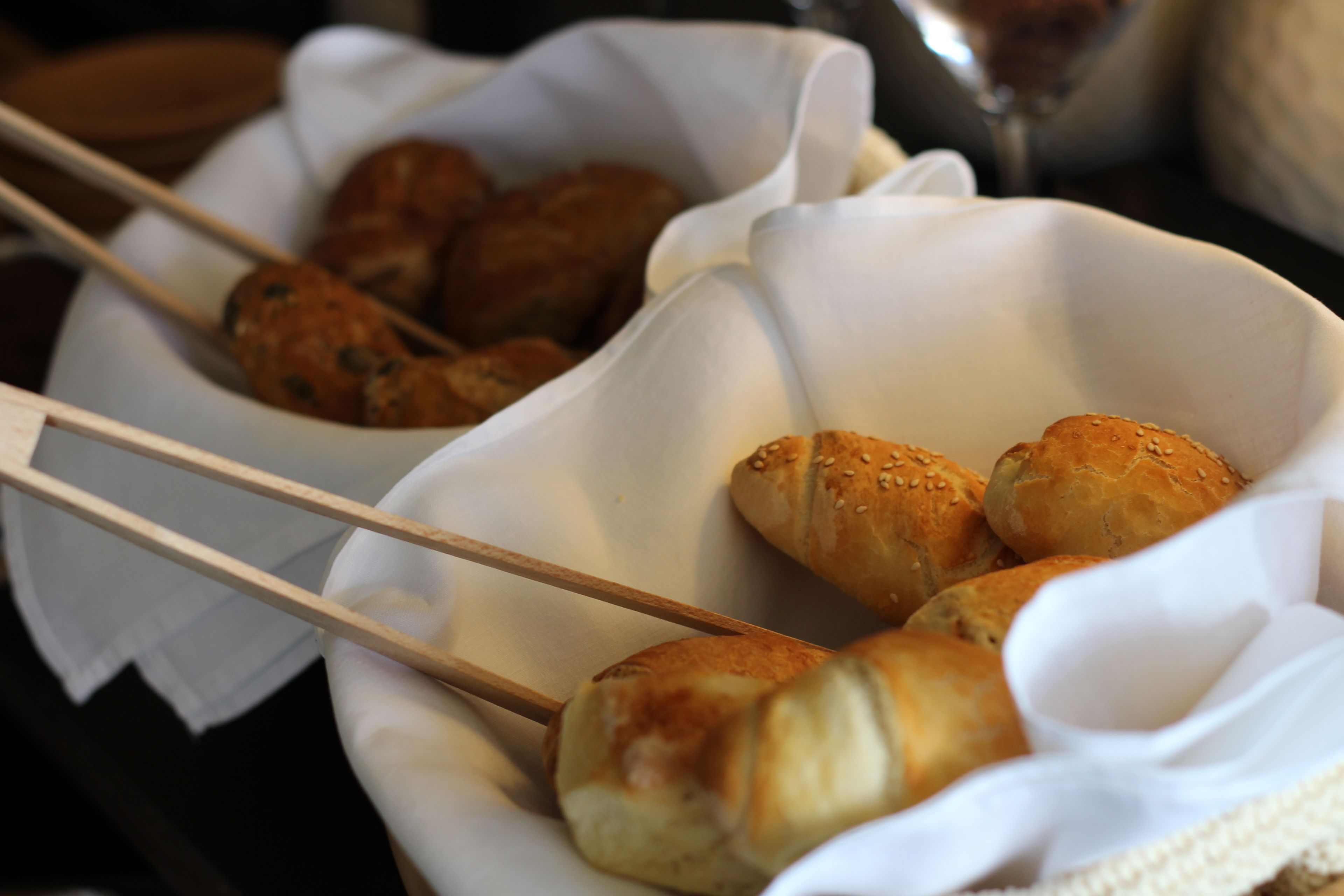 A basket containing skewers of food and rolls.