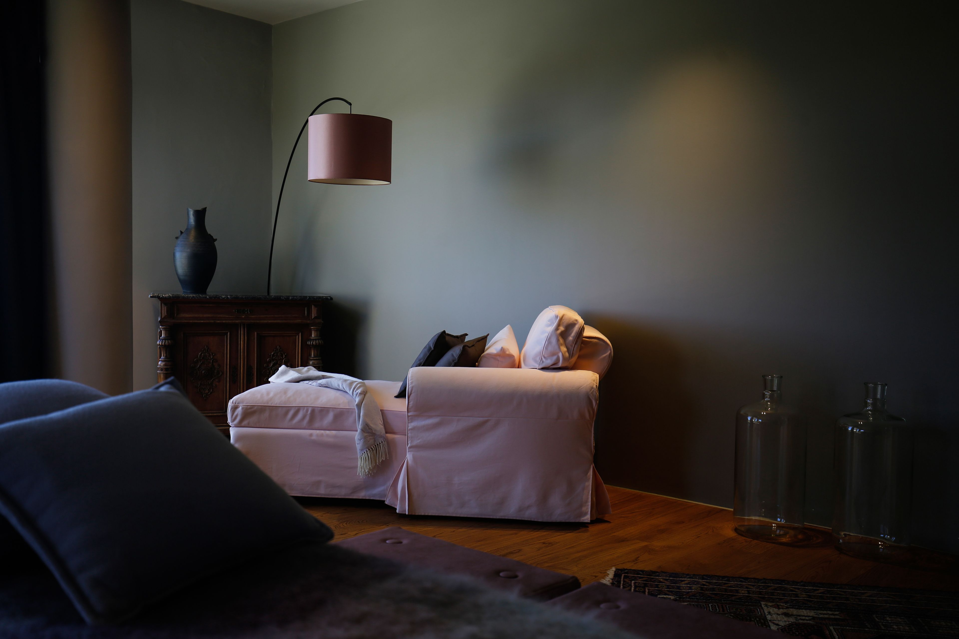 A dimly lit room with a sofa, a small table, and a lamp.