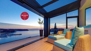 A modern hotel room with a large balcony overlooking a body of water and a cityscape. - Hotel Valsabbion (Medulin)