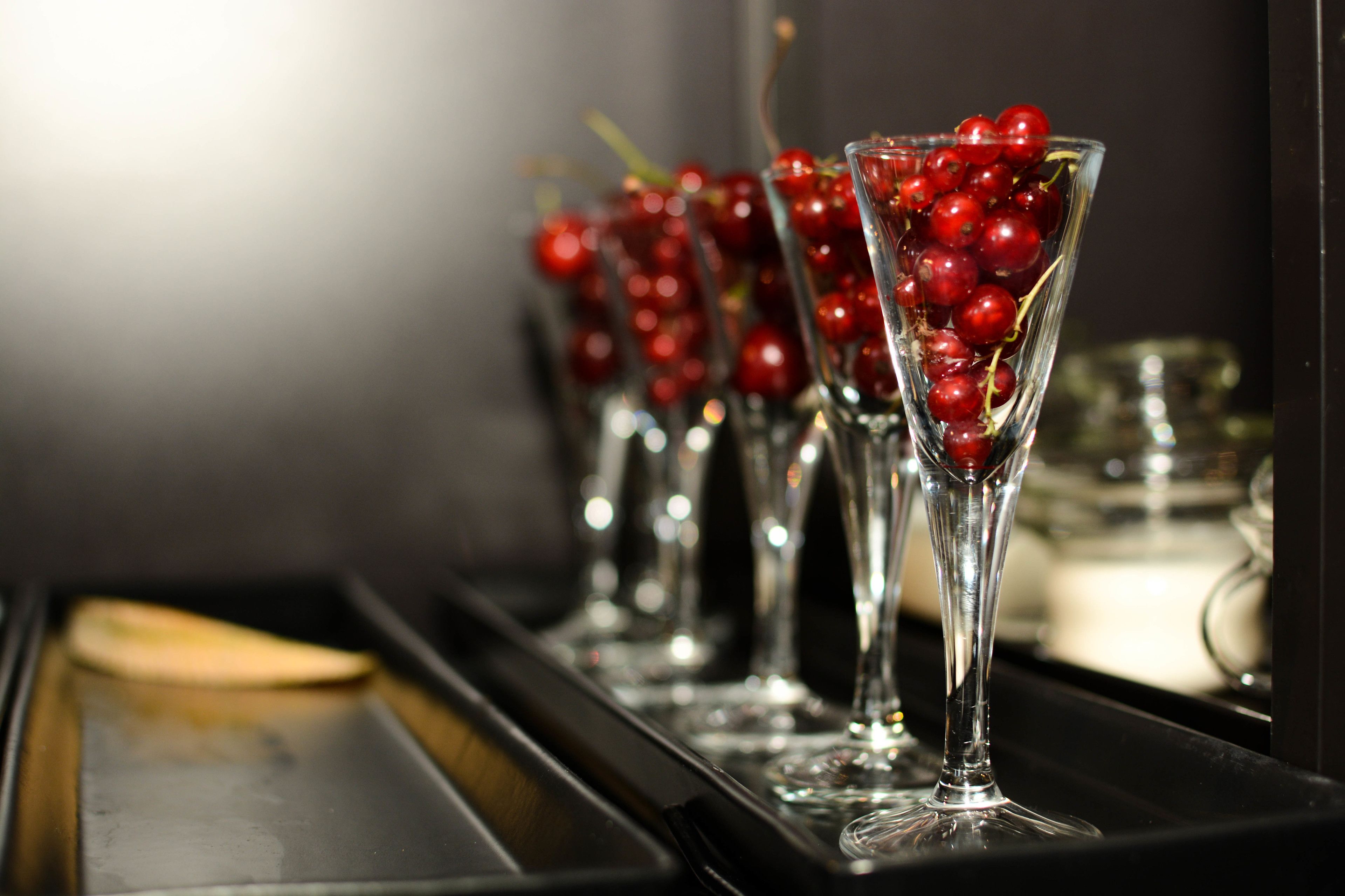 A row of tall glasses filled with red berries, likely for a festive occasion.