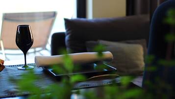 A glass of red wine on a table with a rolled-up menu, a laptop, and a chair in the background.