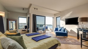 A modern hotel room with a large bed, a desk, a TV, and a view of the city. - Hotel Valsabbion (Medulin)