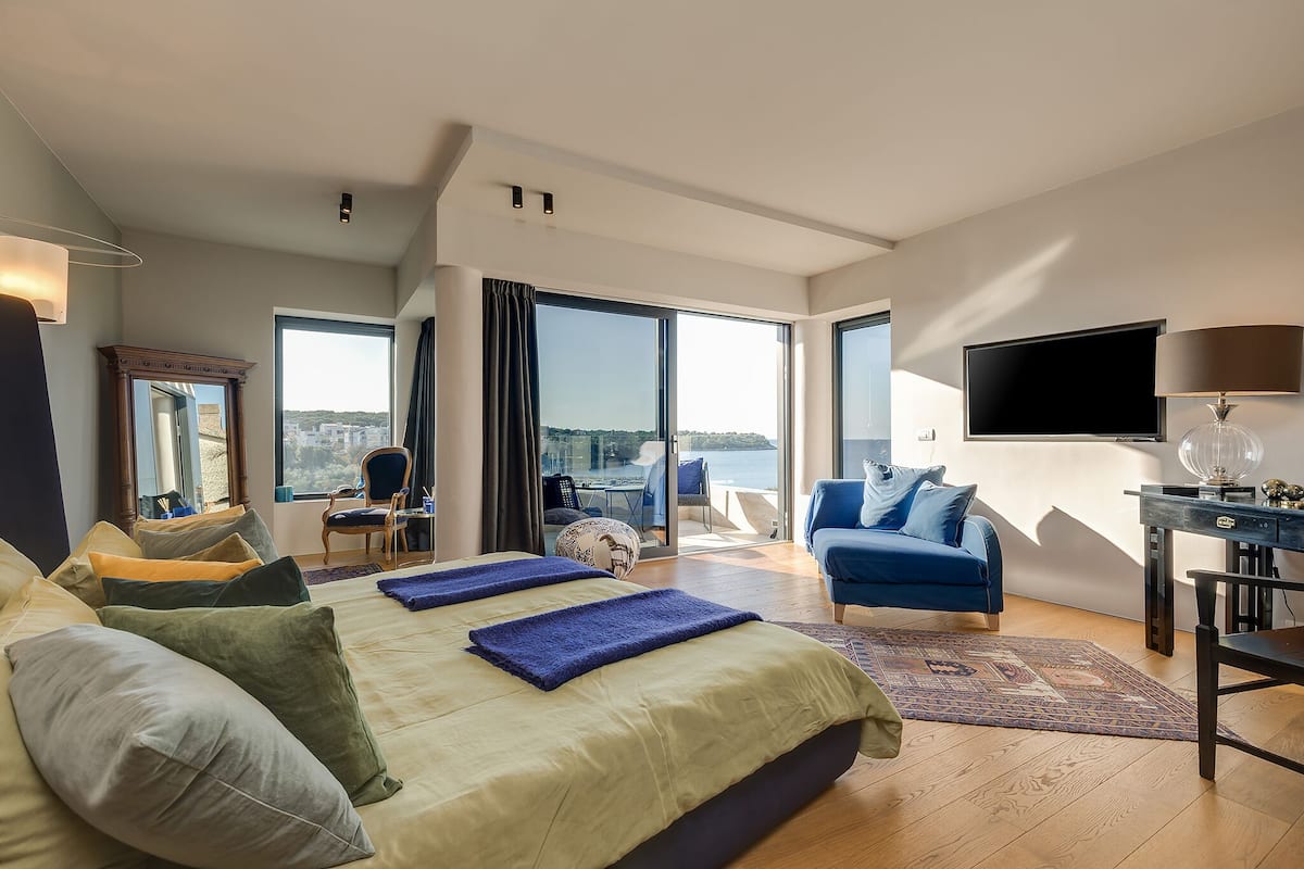 Une chambre d’hôtel moderne, dotée d’un grand lit, d’un bureau, d’une télévision et offrant une vue sur la ville.