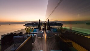 A deck with seating and a view of a body of water at sunset. - Hotel Valsabbion (Medulin)