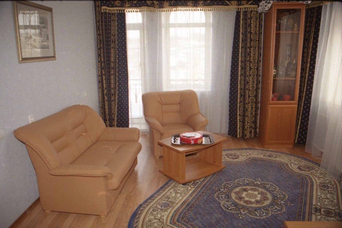 A living room with a beige sofa, a wooden coffee table, and a patterned rug.