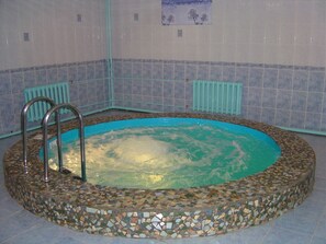 A hot tub with mosaic tiles, metal railings, and a tiled wall with a poster. - Aristokrat (Sergiyev Posad)