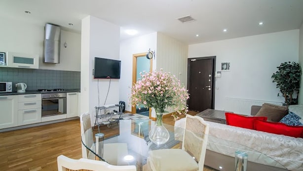 A modern living room with a glass dining table, a sofa, and a TV. - Rustaveli Besiki Apartments (Tbilisi)