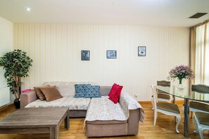 A living room with a sofa, a coffee table, and a dining area with chairs and a glass table. - Rustaveli Besiki Apartments (Tbilisi)