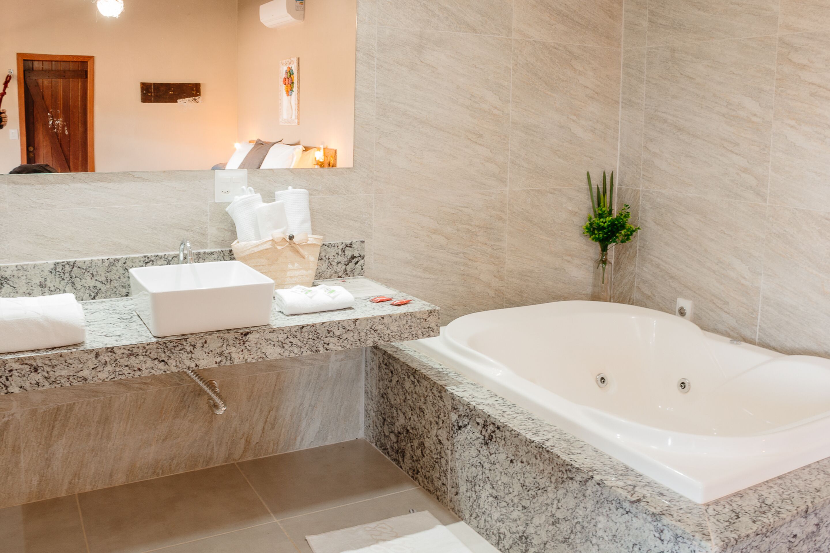Ein modernes Badezimmer mit Marmorwaschbecken, einer großzügigen Badewanne und einem Spiegel über dem Waschbecken.