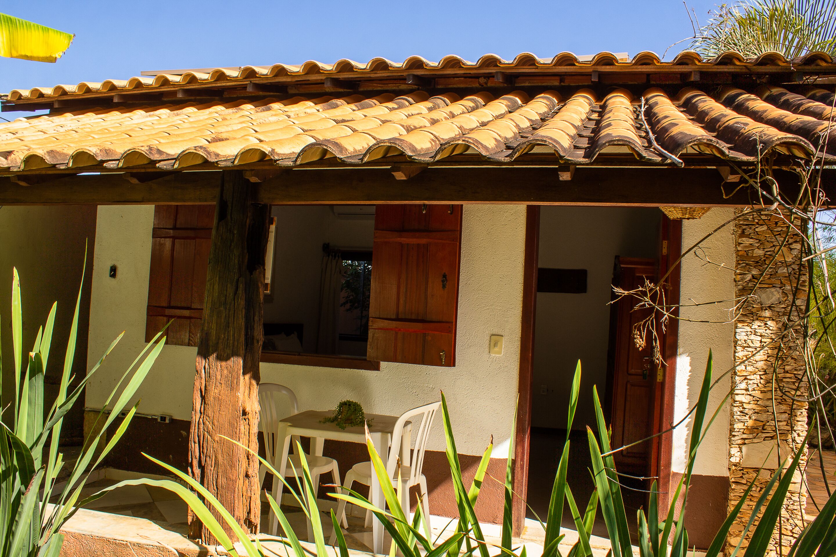 Una casa con techo de tejas, un área de comedor con mesa y sillas, y un acceso a una habitación interior.