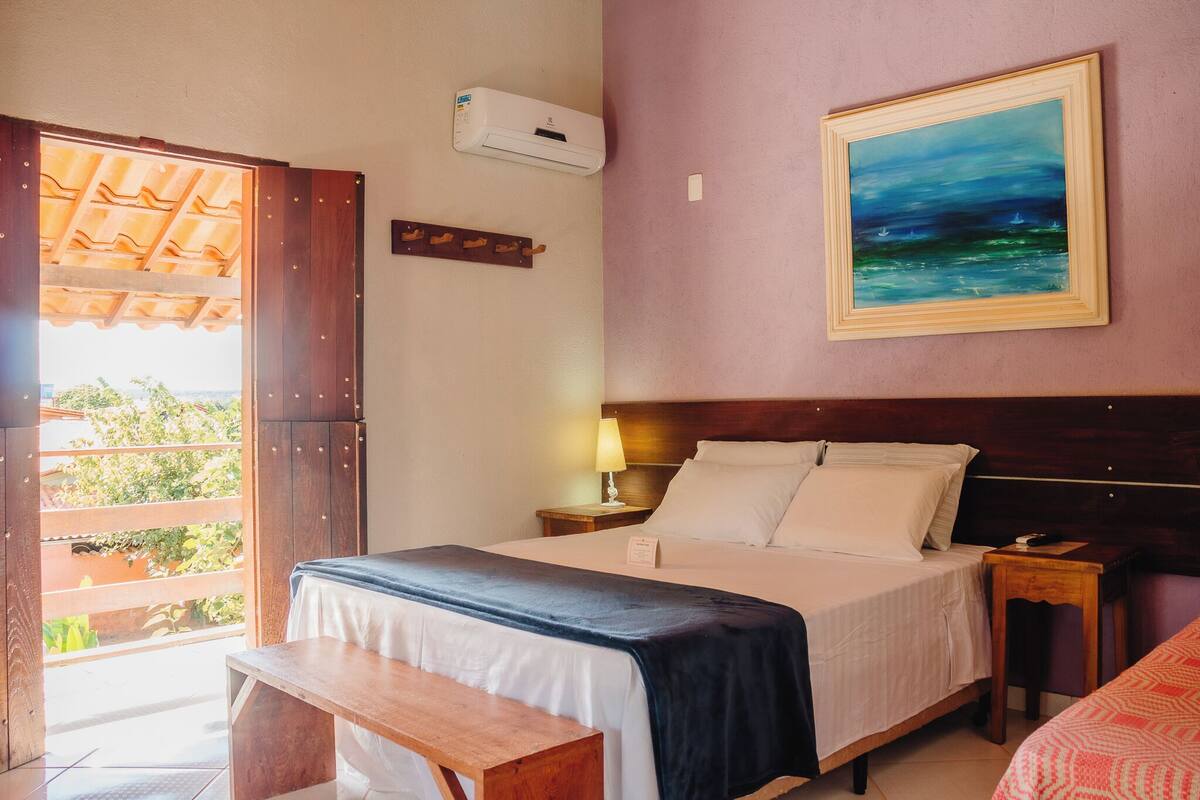 A bedroom with a bed, bedside table, and a painting on the wall.