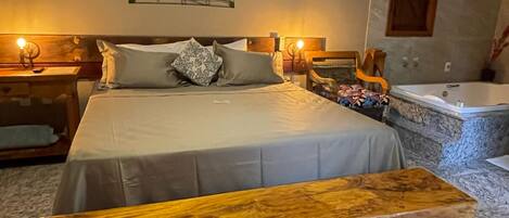 A bedroom with a large bed, a wooden bench, a green area rug, a wall-mounted air conditioning unit, and a bathtub.