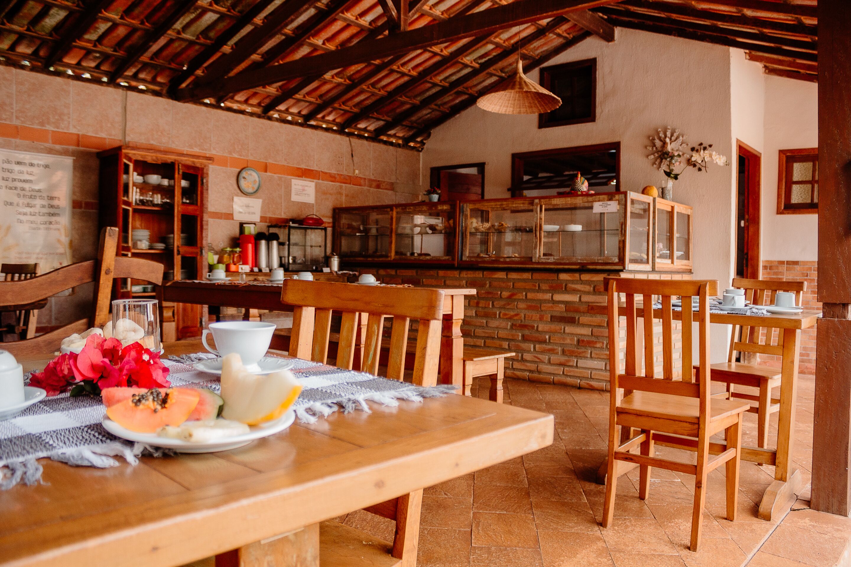 A rustic dining area with wooden furniture, a brick wall, and a tiled floor.