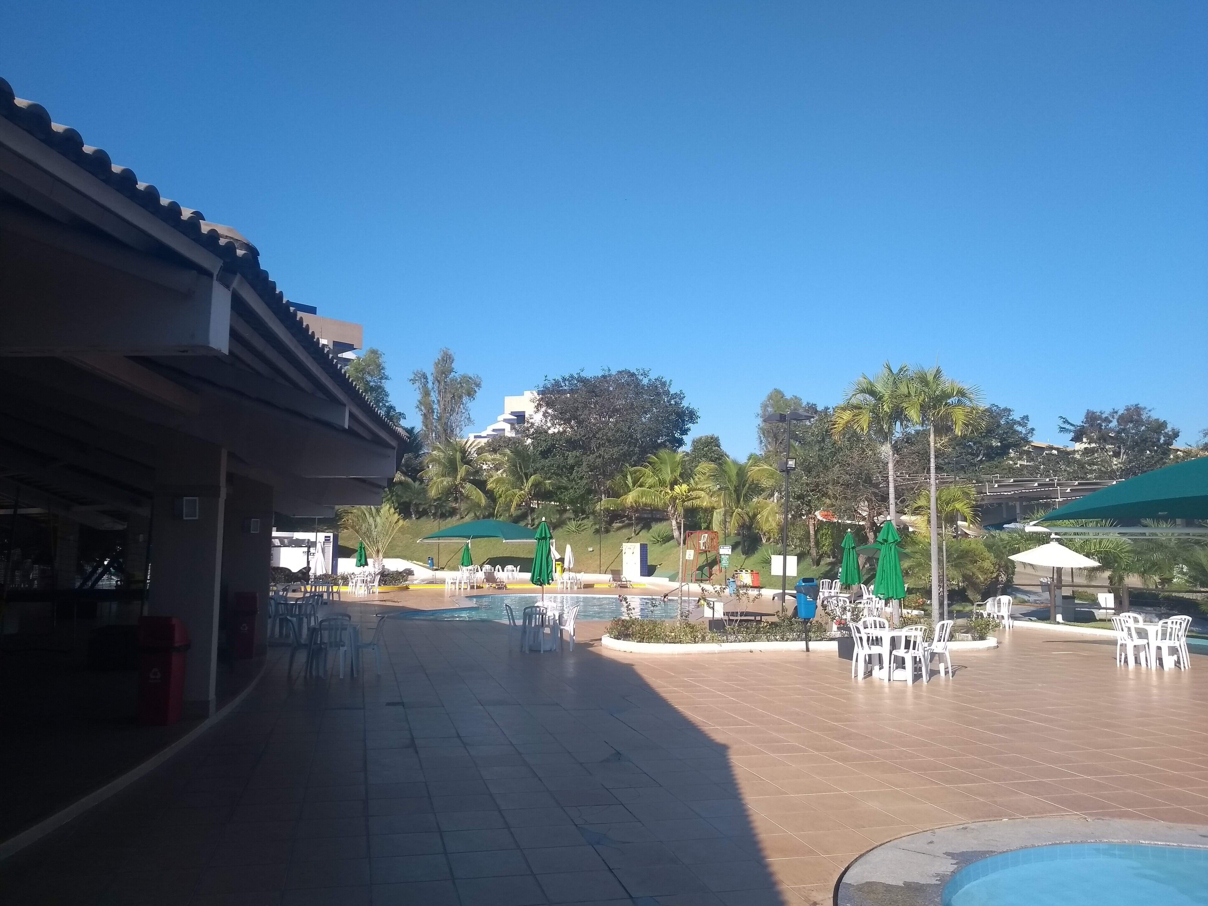 A poolside area with outdoor seating and a building with a tiled roof.