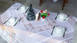 A table set with white teacups, saucers, and plates, a small Christmas tree, and a vase with red and white flowers. - Hotel Pousada WS (Ipojuca)