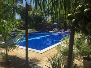 A swimming pool surrounded by palm trees and lounge chairs.