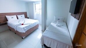 A hotel room with two beds, each with a heart-shaped towel arrangement, white bedding, and a wooden headboard. - Hotel Pousada WS (Ipojuca)