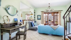 A cozy room with a bed, a desk, a chair, a sofa, and a dining area.