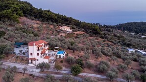 A hillside property with a large building featuring multiple balconies and a swimming pool.