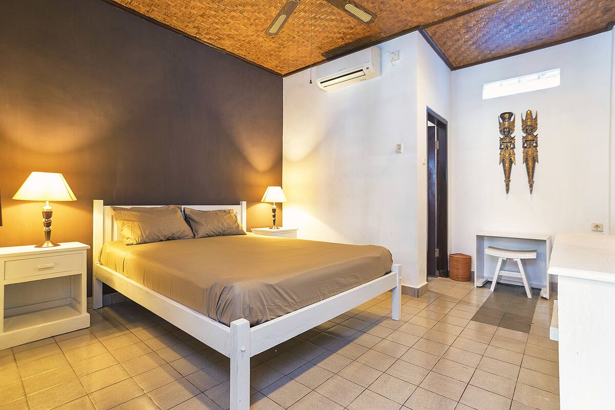 A bedroom with a bed, nightstands, a desk, and a chair.