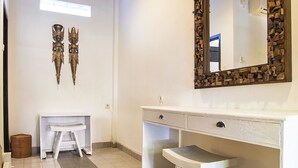 A bathroom with a wooden ceiling, a large mirror, and a white vanity. - Puri Agung Homestay (Kuta)