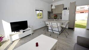 Una cocina moderna con comedor, televisor de pantalla plana y una pequeña mesa con una vela roja.