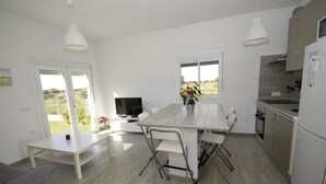 Una cocina moderna con comedor, muebles blancos y un amplio ventanal con vistas al exterior.