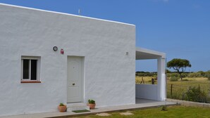 Un edificio moderno blanco con una puerta, un ventanal pequeño y un área exterior cubierta.