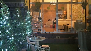 Ein gemütlicher Außenbereich mit Weihnachtsbaum, einem Neon-Schild mit der Aufschrift „TAKE ME HOME“ und einem sichtbaren Schild einer Zahnklinik.