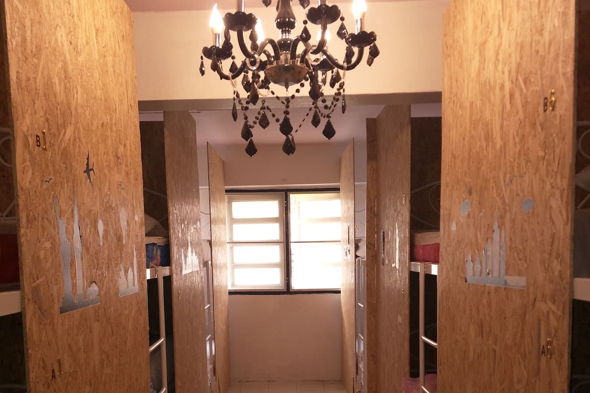 A corridor with wooden walls, a chandelier, and a window at the end.