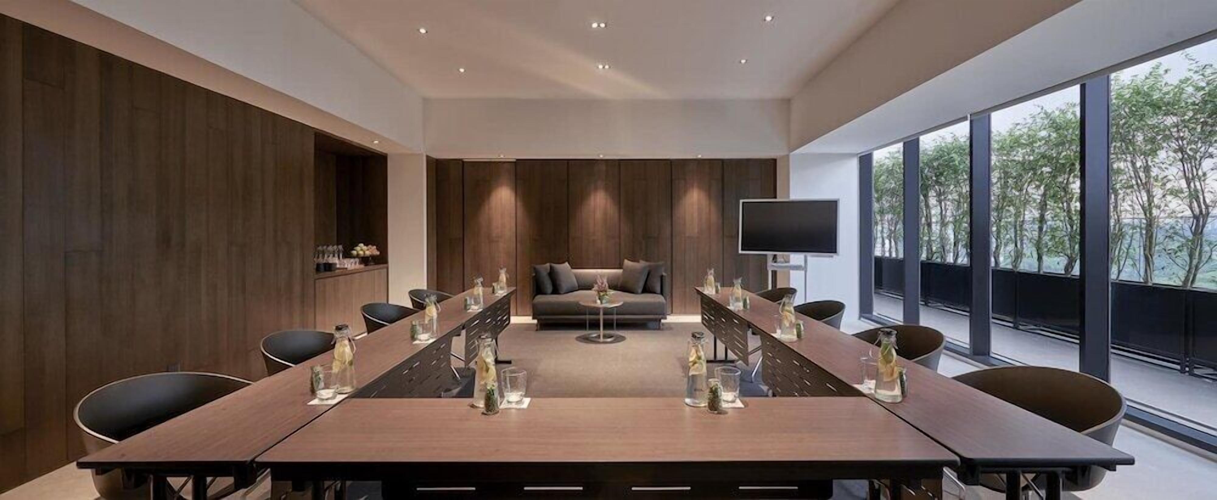 A conference room with a long table, chairs, a sofa, and a TV.