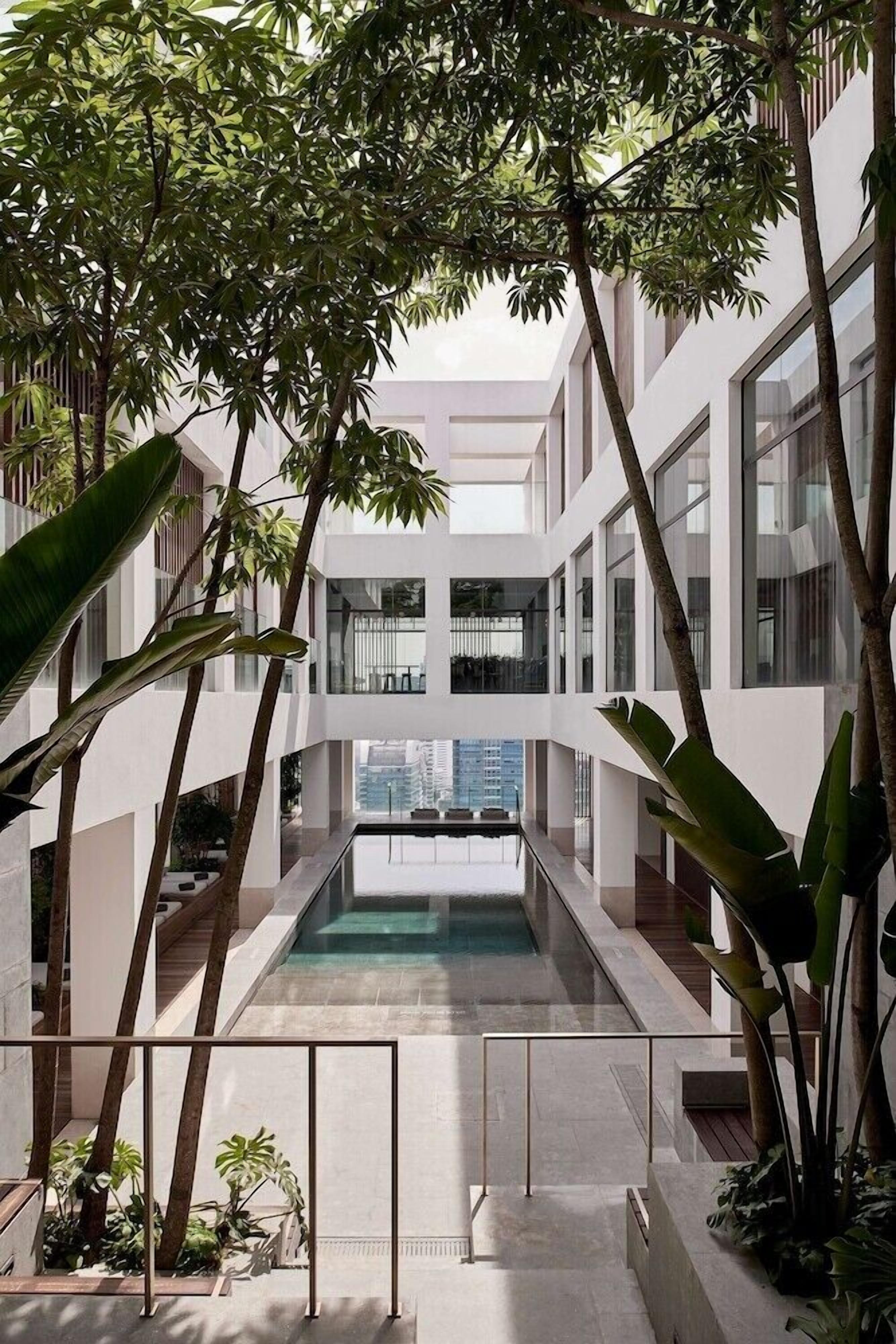 A modern building with a central pool, surrounded by large windows and indoor plants.