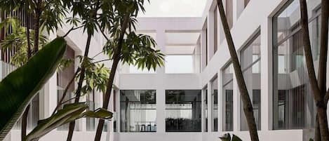 A modern building with a central pool, surrounded by large windows and indoor plants.