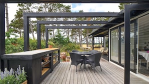 A wooden deck with outdoor furniture, a built-in bar, and a glass enclosure. - Gorgeous home in Ebeltoft with kitchen (Ebeltoft)