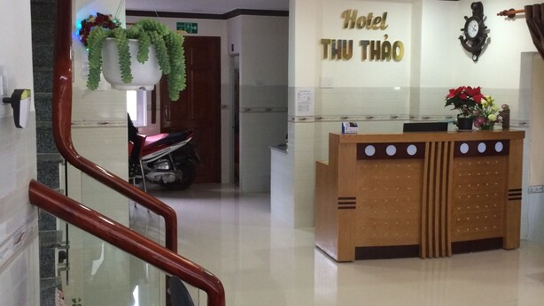 A hotel reception area with a wooden reception desk, a clock, and a sign that reads "Hotel Thu Thao". - Hotel Thu Thao (Phan Rang)