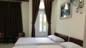 A hotel room with two beds, a chair, a desk, and a window with curtains. - Hotel Thu Thao (Phan Rang)