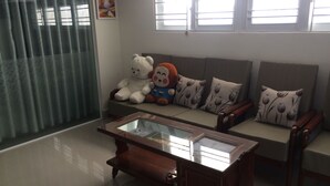 A living room with a sofa, two large stuffed animals, a glass-top coffee table, and a painting on the wall. - Hotel Thu Thao (Phan Rang)